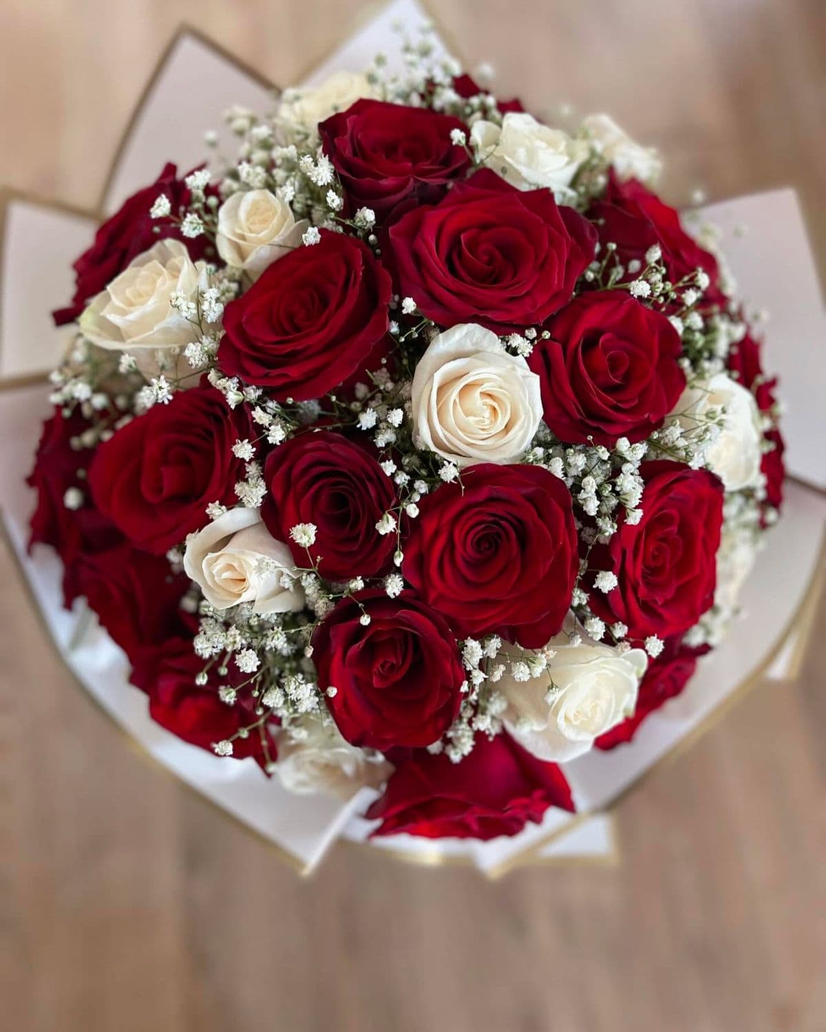 Red and white roses with baby's breath in ivory wrapping
