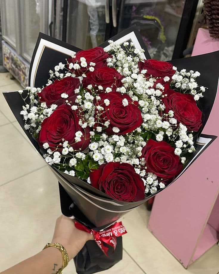 Deep red roses with abundant baby's breath in black wrapping