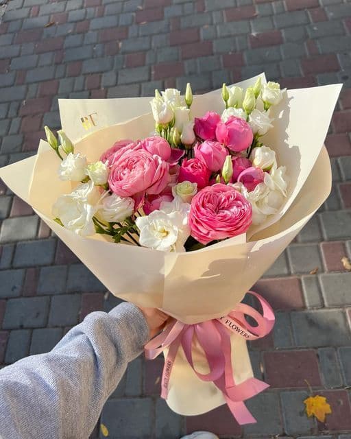 Pink garden roses and spray roses with white lisianthus in cream wrapping
