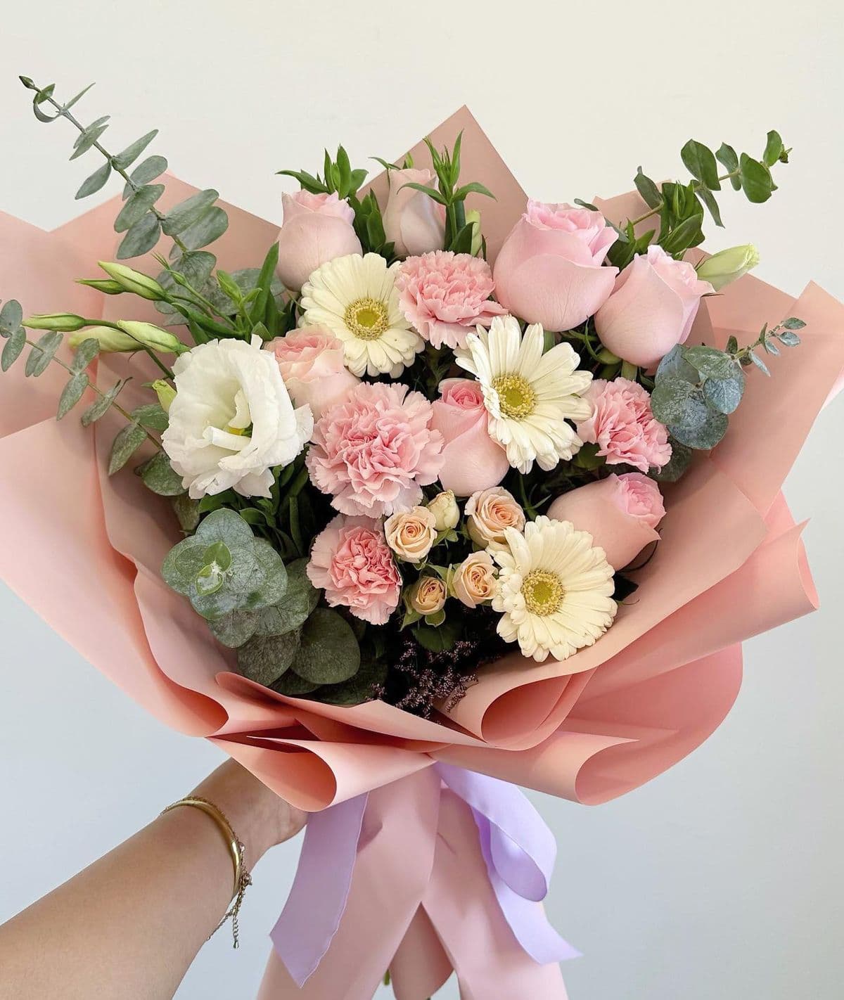 Blush roses, pink carnations, white gerberas, and lisianthus with eucalyptus